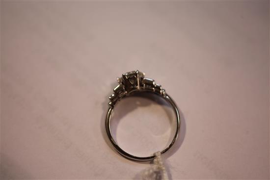 A platinum and single stone diamond ring with graduated emerald cut diamond set shoulders, size N.